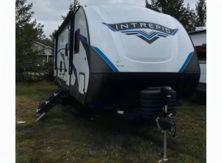 RV rental: White Intrepid travel trailer with blue & black accents, parked outdoors on grass.. Riverside RV Intrepid 2023