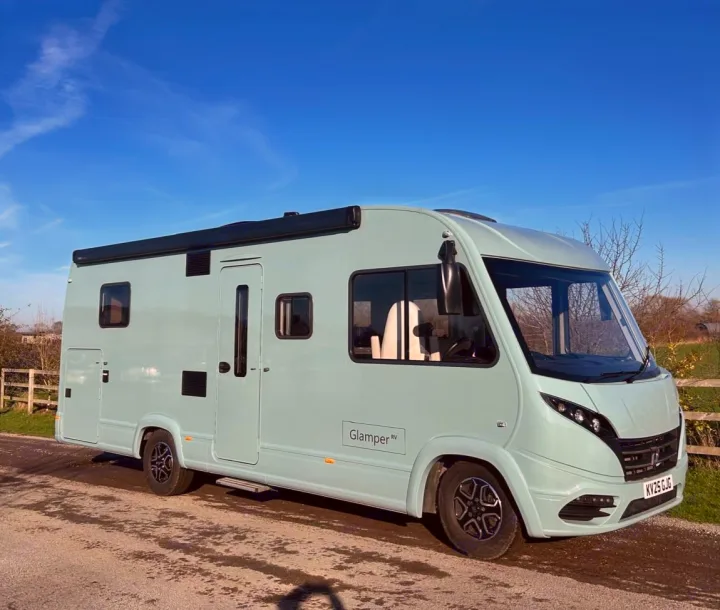 A chic, mint green rv rental by "Glamper RV" is shown parked on a road on a sunny day, perfect for your next trip.. GlamperRV DBL 2025