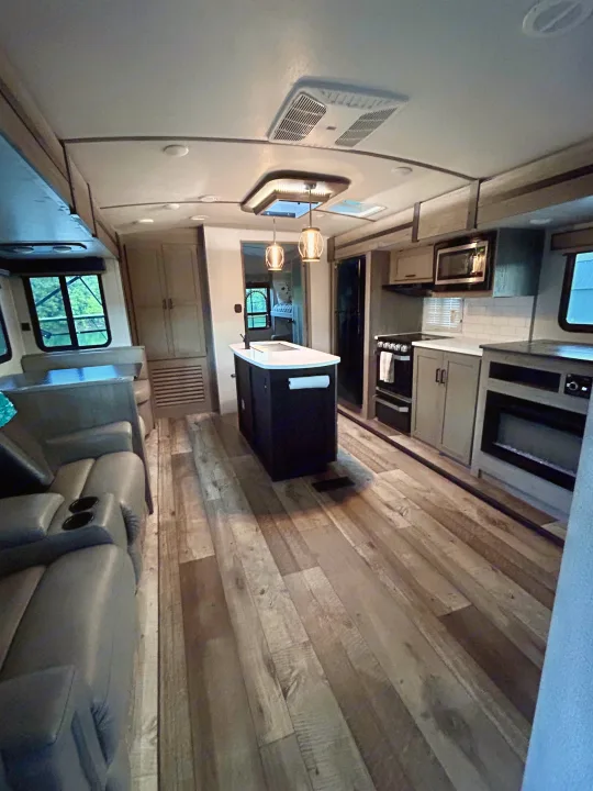 Spacious, modern RV rental interior featuring a full kitchen with island, living area, and comfortable seating.. Keystone RV Outback 2021