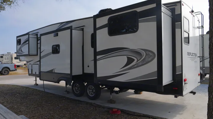 A large Grand Design Reflection fifth-wheel RV rental with slide-outs extended, parked on a concrete pad.. Grand Design Reflection 2022