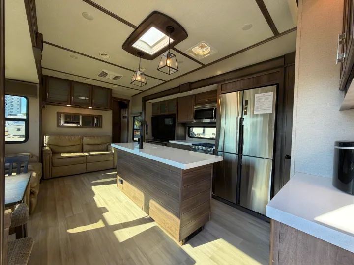Modern RV rental interior showcasing a well-appointed kitchen with island, stainless appliances, and a bright, cozy living space.. Grand Design Solitude 2021
