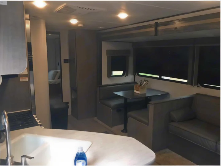 Cozy rv rental interior with kitchen, dining booth, sofa, and bedroom access. A functional and modern camper living space.. Keystone RV Hideout 2021