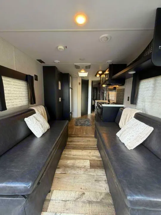 Inviting rv rental interior: modern dark benches, wood-look floor, and a full kitchen for comfortable journeys.. Forest River Wolf Pup 2021