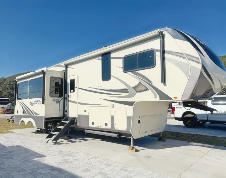 This cream Grand Design Solitude fifth-wheel RV rental is parked with slides extended, ready for adventure.. Grand Design Solitude 2021