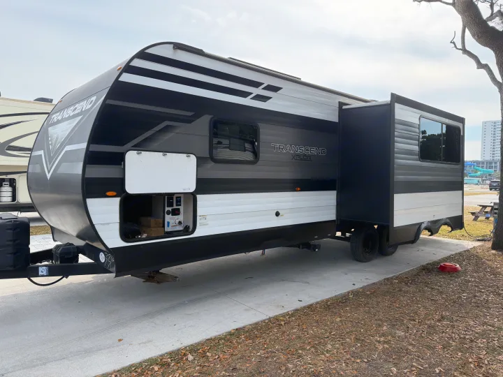 Stylish Transcend XPLOR travel trailer with an extended slide-out, perfect for an rv rental vacation at a sunny park.. Grand Design Transcend 265BH 2022