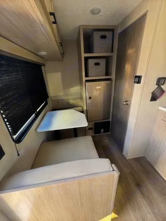 RV rental interior: light wood dinette, overhead cabinets, shelves with bins, mini-fridge, and black window blinds.. 5ZT2CABC9TK012992 Catalina 2026