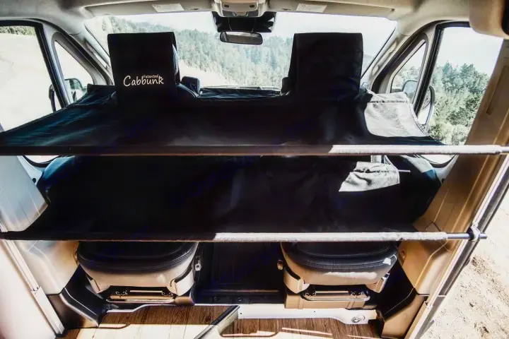 An RV rental's cab features a Cabbunk two-tier bed system installed over the front seats, offering extra sleeping space.. Ram ProMaster 2022