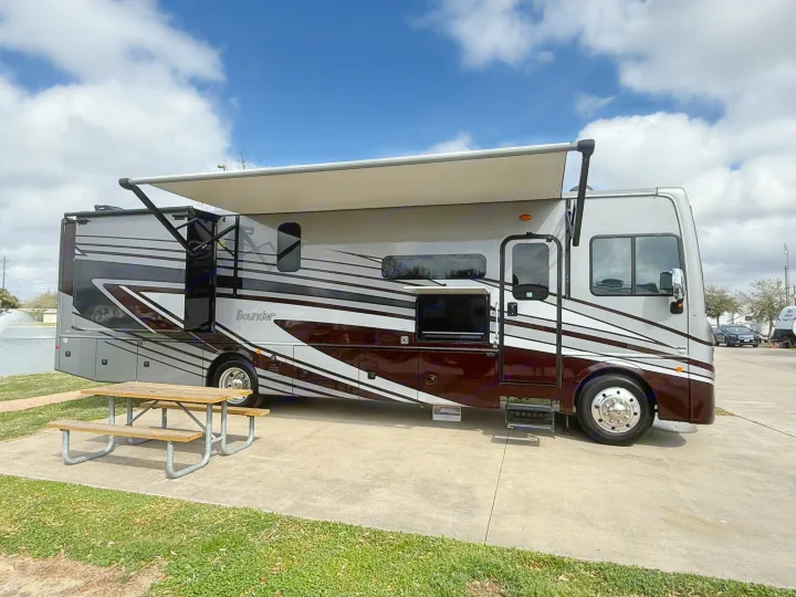 This large RV rental motorhome, with its extended awning & picnic table, is perfectly parked on a sunny day for an outdoor adventure.. Bounder Bounder Motorhome 2024