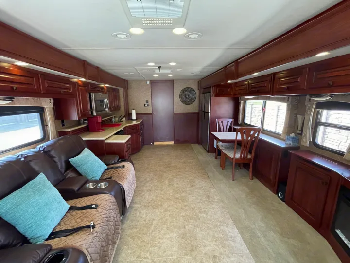 This RV rental features a cozy living space with a brown leather couch, full kitchen, and dining area for travel comfort.. Berkshire Berkshire Motorhome 2013