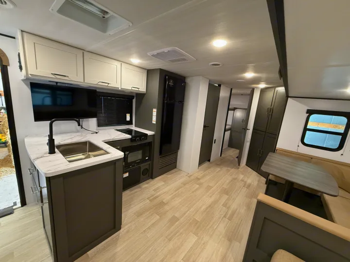 Discover this RV rental's modern interior: full kitchen with sink, microwave, white cabinets, light counters, TV, and dinette.. Keystone Bullet 2026