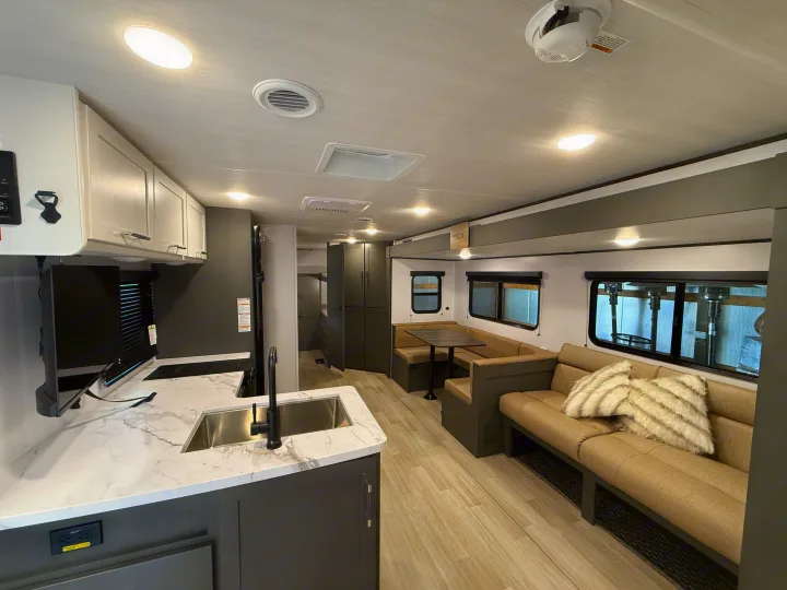 Explore this modern RV rental interior featuring a full kitchen with a sink, U-shaped dinette, and a comfortable sofa. Ideal for travel.. Keystone Bullet 2026