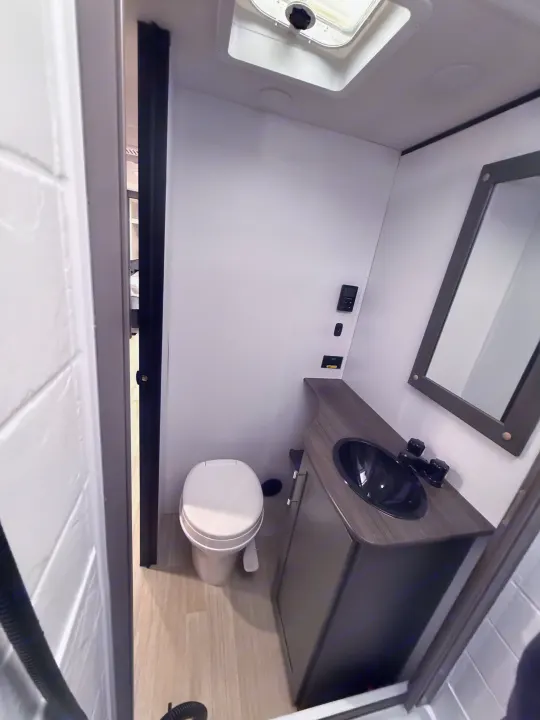 RV rental bathroom: clean, compact, with toilet, dark sink, vanity, mirror, and ceiling vent.. Keystone Bullet 2026