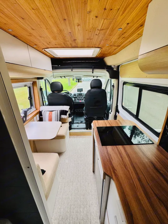 Explore this modern RV rental's inviting interior: a bright wooden ceiling, cozy dinette, and sleek kitchenette await your next adventure.. Custom Camper 2021