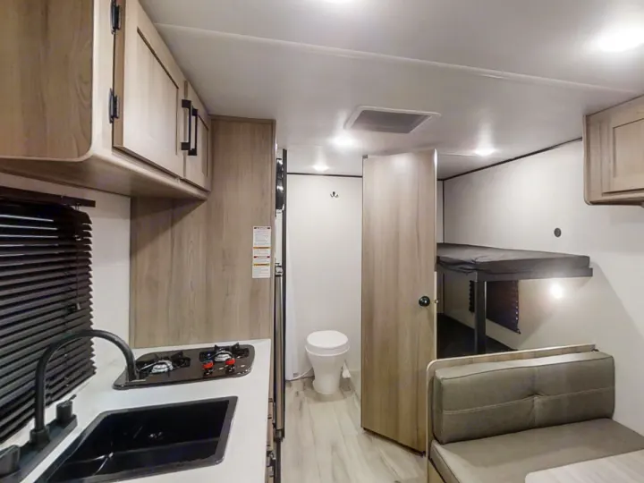 Cozy RV rental interior with kitchen, bathroom, and bunk beds, perfect for family adventures on the road.. Keystone RV Coleman 2025