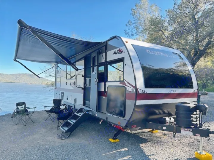 This sleek travel trailer RV rental, with an extended awning, sits lakeside, ready for adventure.. Forest River Campsite Reserve 2026