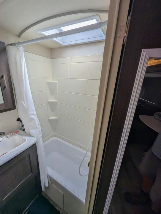 Compact RV rental bathroom with shower/tub combo, sink, and bright skylight overhead. Ideal for on-the-go living.. Forest River Salem Cruise Lite 2018