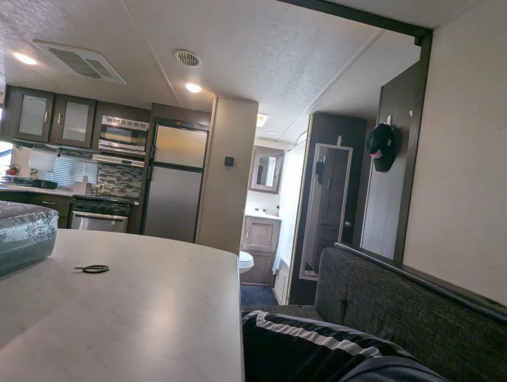 This RV rental interior shows a compact kitchen, dining area, and bathroom, offering a functional travel space.. Forest River Salem Cruise Lite 2018