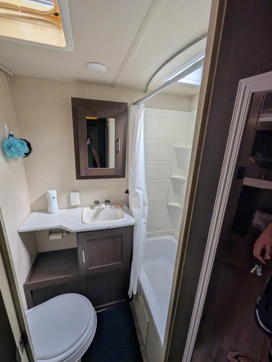 Compact **RV rental** bathroom featuring a toilet, vanity with sink, mirror cabinet, and shower/tub combo. Functional space.. Forest River Salem Cruise Lite 2018