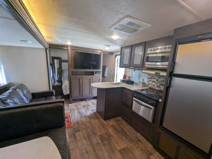 Spacious RV rental interior with full kitchen, living area, and bedroom access. Features dark wood finishes & modern appliances.. Forest River Salem Cruise Lite 2018