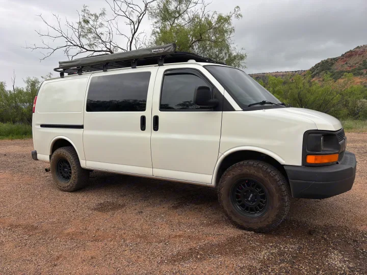 White Chevy off-road van with Rhino-Rack awning, all-terrain tires. Perfect RV rental for adventure.. Chevrolet Express 1500 AWD 2007