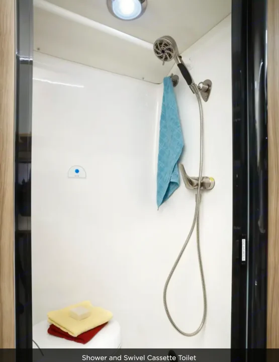 Compact RV rental bathroom: shower, blue towel, and swivel cassette toilet with soap & towels.. Coachmen Pixel 2025