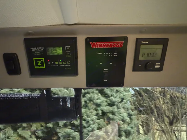 RV rental interior showing Winnebago, Zamp Solar, and Truma control panels for managing power, water, and heating.. Winnebago Solis 2025