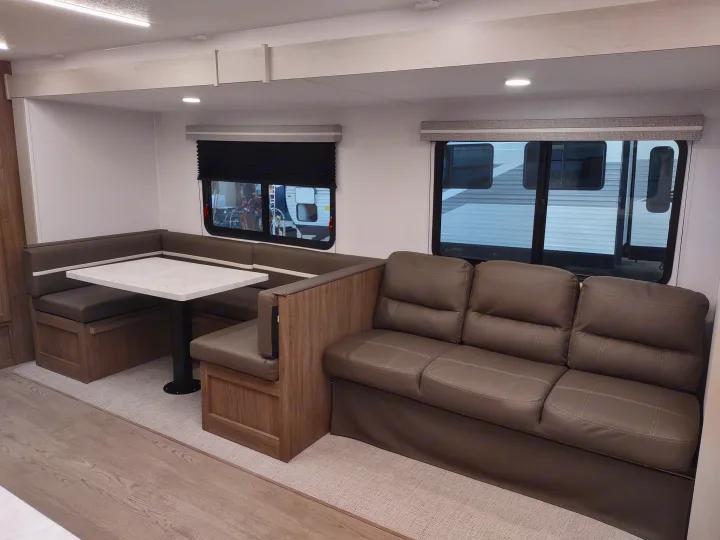 Spacious rv rental interior featuring a gray U-shaped dinette, comfortable sofa, and large windows.. Coachmen 29 SE 2025