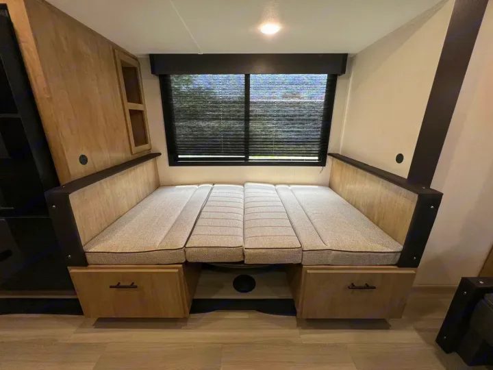 This rv rental features a cozy interior with a dinette transformed into a bed, offering comfort and under-bed storage.. Forest River Campsite Reserve 2026