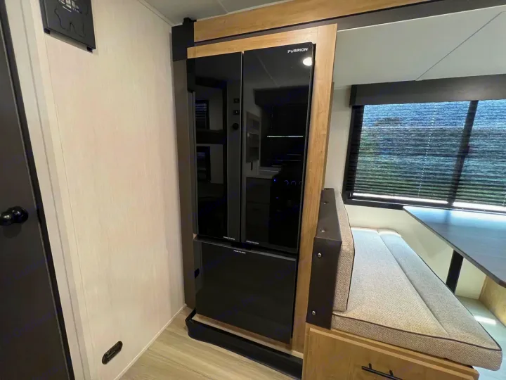 RV rental interior showcasing a modern black Furrion refrigerator and a cozy dinette with window blinds.. Forest River Campsite Reserve 2026