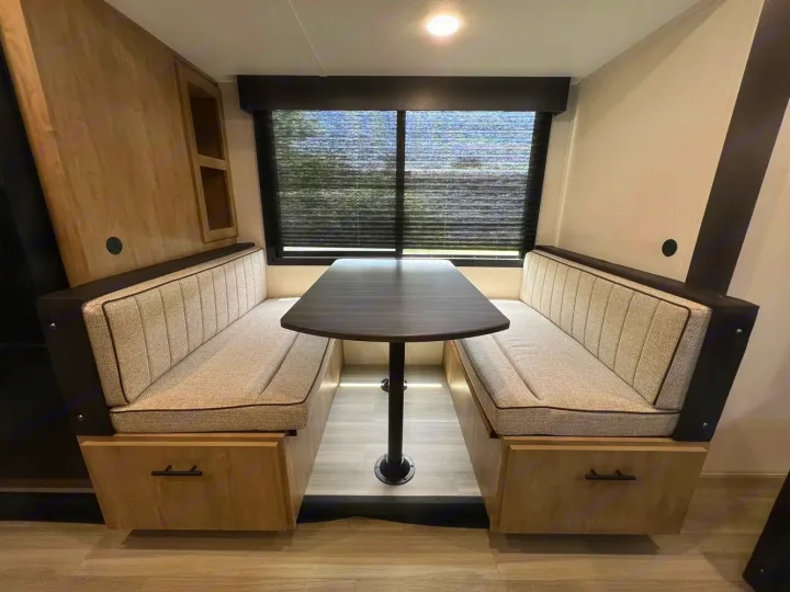 Cozy RV rental dinette with booth seating, under-seat storage, and a large window with privacy blinds for travel.. Forest River Campsite Reserve 2026