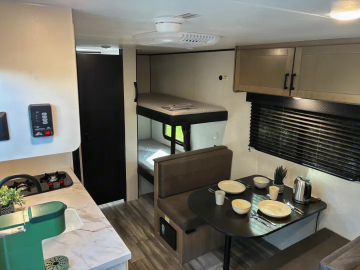 Inside a modern RV rental: well-equipped kitchen, dining booth, and cozy bunk beds for comfortable travel.. Jayco Jay Flight SLX 2026