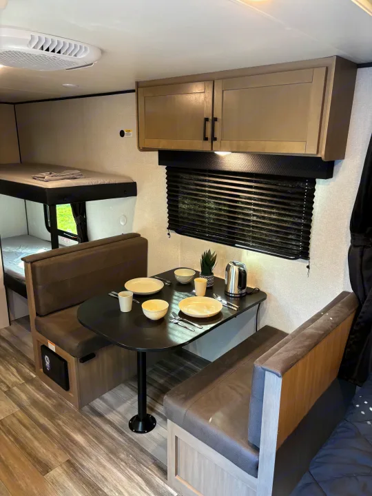 Modern RV rental interior: dinette with tableware, bunk beds, and overhead storage. Compact and functional space.. Jayco Jay Flight SLX 2026