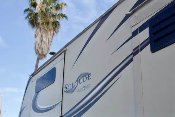Luxury Solitude Grand Design RV rental with striking blue stripes, a window, and a palm tree against a blue sky.. Grand Design Solitude 2015