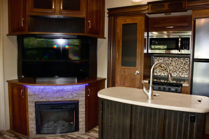 Experience comfort in this RV rental! Features a modern kitchen, cozy fireplace, and large TV in a well-appointed living space.. Grand Design Solitude 2015