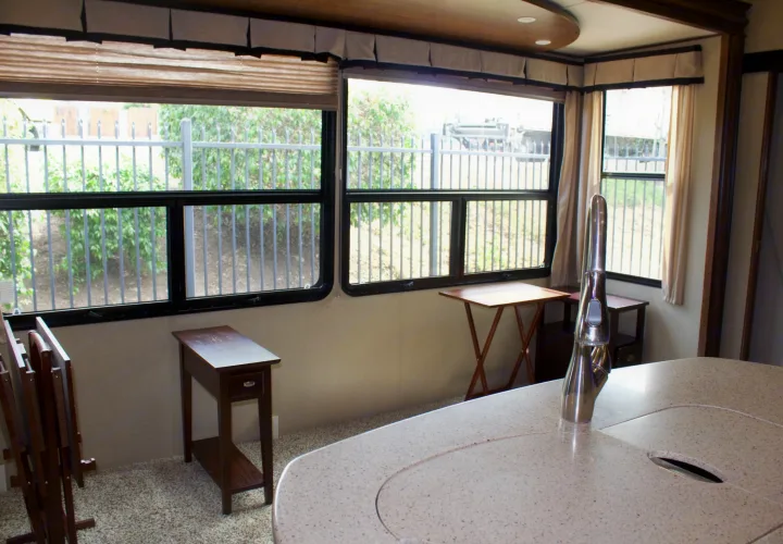 Bright RV rental interior with large windows, a modern kitchen island, and cozy wooden furniture for a relaxing stay.. Grand Design Solitude 2015