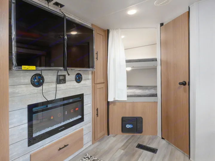 Modern RV rental interior with bunk beds, a cozy fireplace, and TV setup. Perfect for family adventures.. Prime Time Avenger 2024