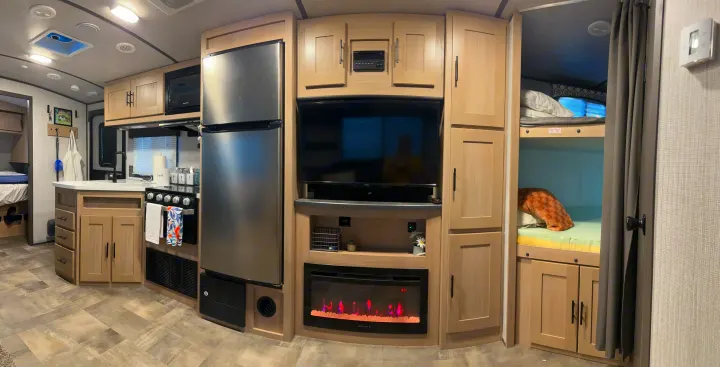 Modern RV rental interior: full kitchen with fridge, living area with TV & fireplace, plus cozy bunk beds.. Cruiser RV Radiance Ultra Lite 2020