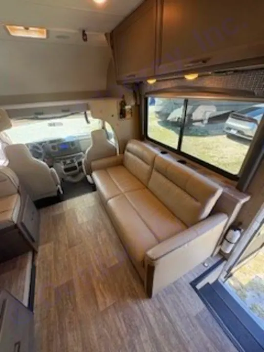 RV rental interior: A bright living space with a comfy sofa, wood-style floor, and driver's cabin visible.. Thor Chateau 2023