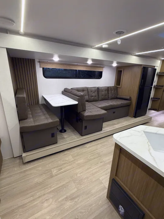 Cozy RV rental interior with modern dinette, sectional sofa, and kitchen area. Perfect for travel comfort.. Forest River Salem Cruise-Lite 2026