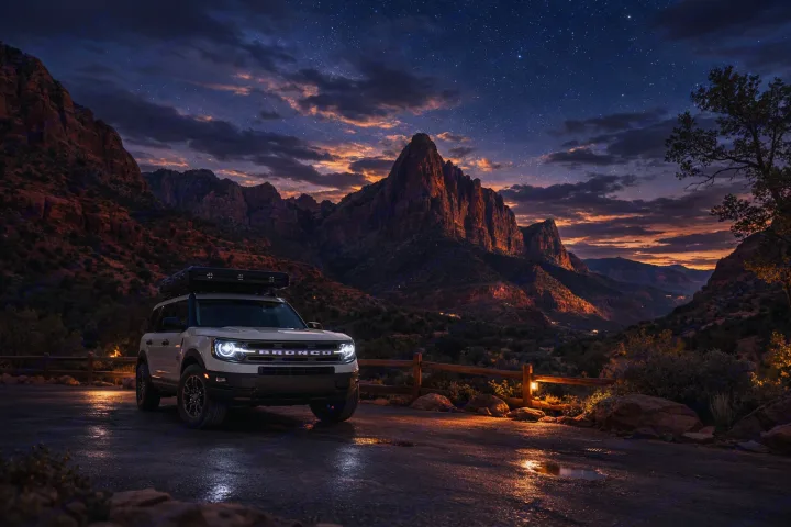 A white Bronco Sport with rooftop tent, perfect as an rv rental, parked on a wet road at dusk with dramatic, star-filled mountains.. Ford Bronco Sport 2024