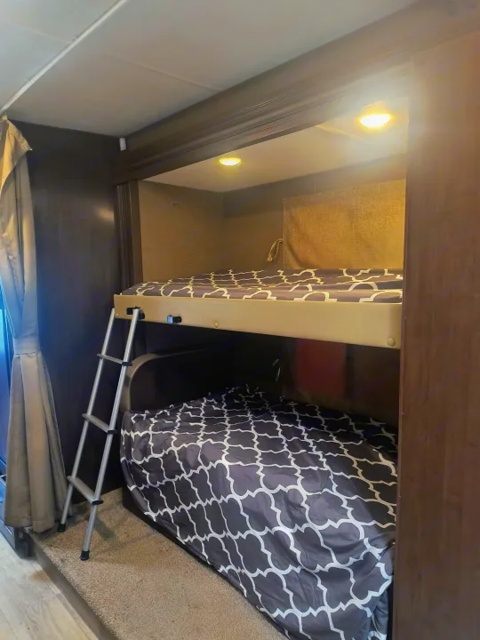 RV rental: Cozy bunk beds with ladder, overhead lighting, and patterned bedding offer a comfortable space.. Thor Motor Coach Freedom Elite 2019