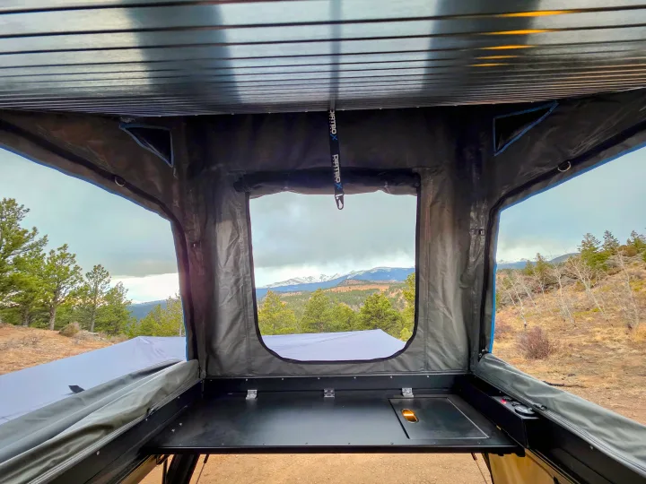 Scenic mountain view from inside an RV rental rooftop tent, featuring a built-in counter for your outdoor camping adventure.. Dirtbox Overland Canopy Camper 2023