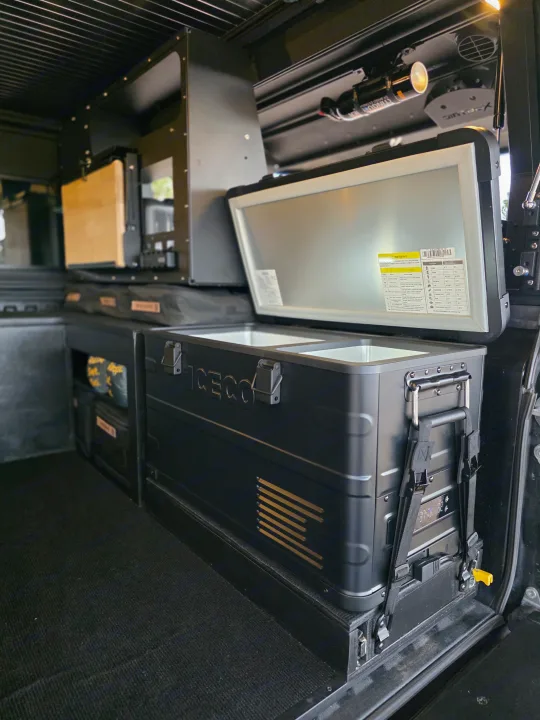 This RV rental's organized interior features an ICECO fridge/freezer, modular storage, and a safety extinguisher.. Dirtbox Overland Canopy Camper 2023