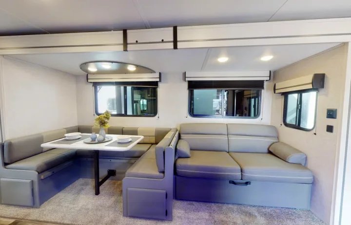 RV rental interior with a grey U-shaped dinette and sofa bed, ideal for dining and relaxing in a modern space.. Crossroads RV Volante 2023