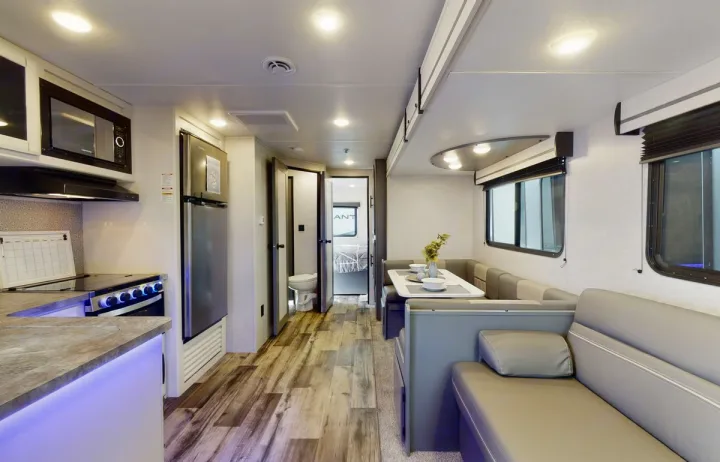 Spacious RV rental showcasing a full kitchen with microwave & stove, dinette, and sofa. Bright, wood-look flooring.. Crossroads RV Volante 2023