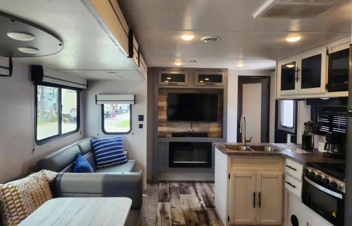 Modern RV rental interior showcasing a cozy living area, entertainment center with TV & fireplace, and a functional kitchen.. Crossroads RV Volante 2023