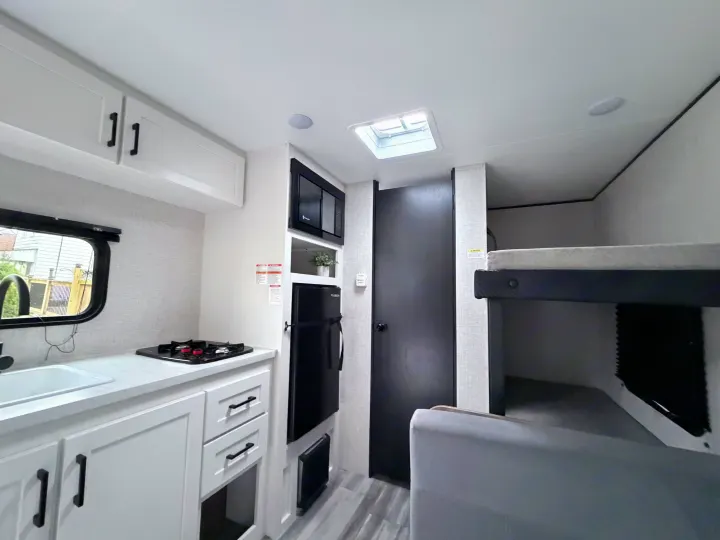 Compact and modern RV rental: Kitchenette with stove, sink, fridge, and cozy bunk beds.. Jayco 2025 Jay Flight SLX 2025