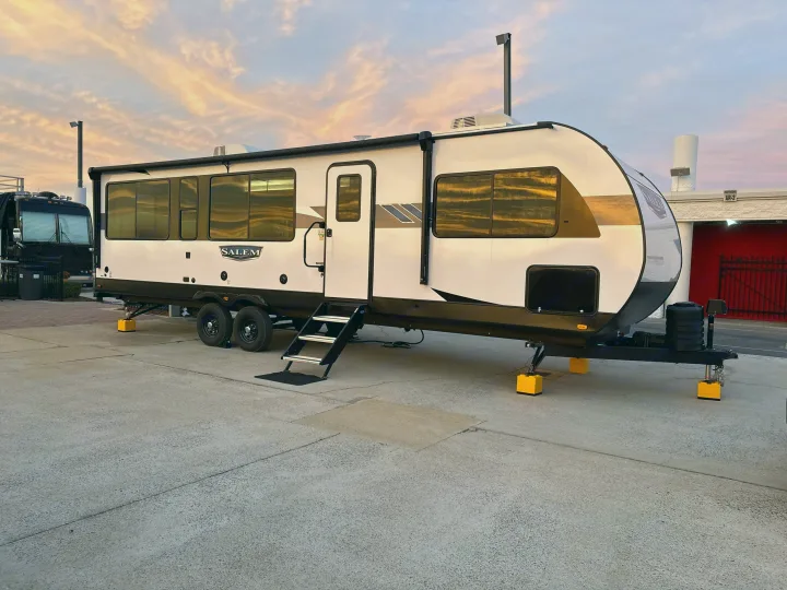 RV rental: A white Salem travel trailer parked on concrete, steps down. Beautiful pink and orange sunset sky reflecting in windows.. Forest River Salem 2024