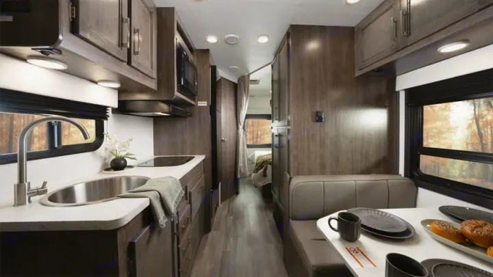 Inside this rv rental, a modern kitchen with a sink, dining area, and hallway to the bedroom, set for adventure.. Entegra Odyssey SE 2026