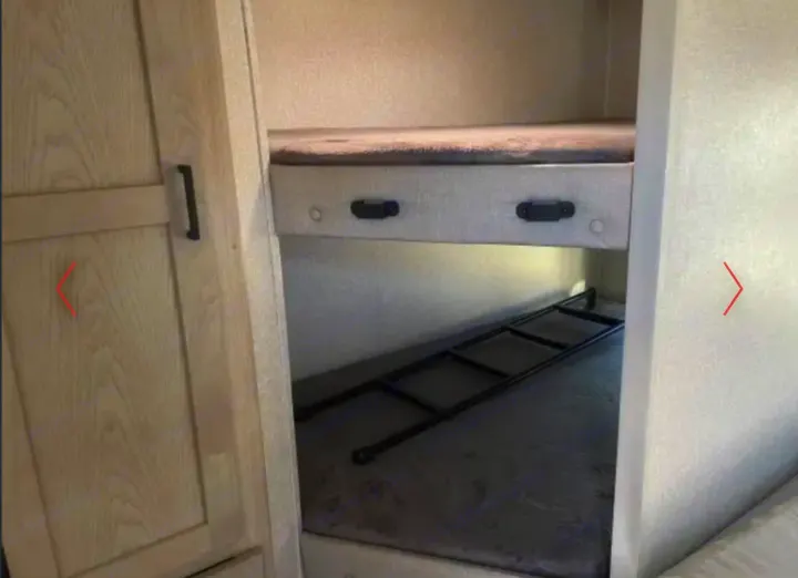 Bunk beds in an RV rental, with a ladder resting on the lower bunk, ideal for family travel accommodations.. Alto East West 2024